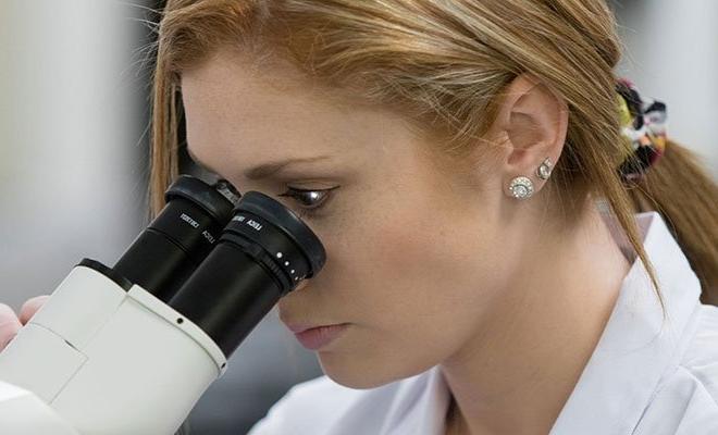 Person looking into microscope, biotechnology program